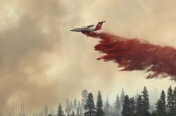 airplane dropping load of fire retardant over wildfire