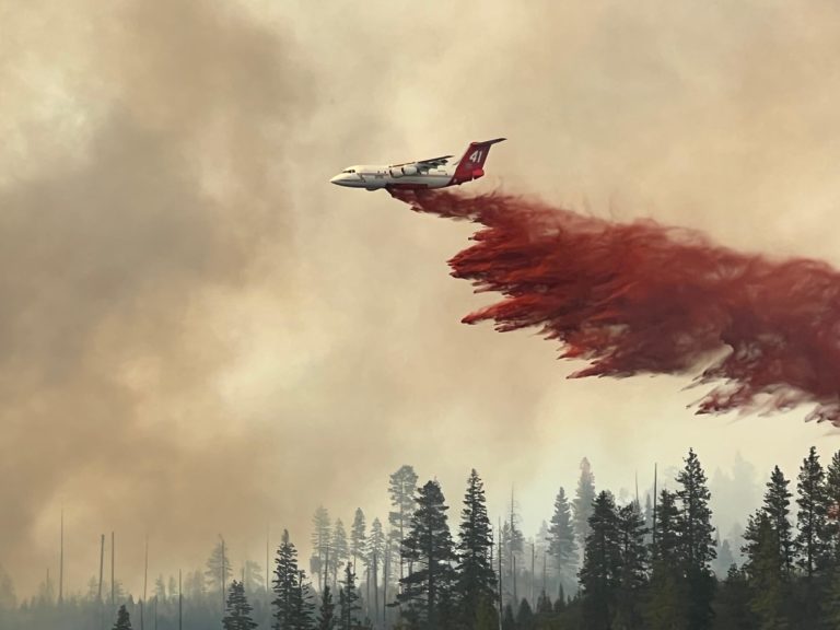 airplane dropping load of fire retardant over wildfire 