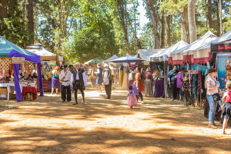 Canterbury Renaissance Faire main village walk with colorful tents lining the street under tree canopy